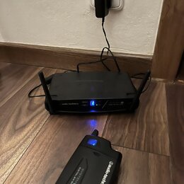 Černý bezdrátový systém značky audio-technica, který se skládá z přijímače a vysílače. Na obou zařízeních je bílý nápis audio-technica a označení SYS…