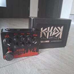 Černý efekt pedál s červenými grafickými prvky a nápisy. Na horní straně jsou čtyři ovládací knoflíky s popisky VOL, DRIVE, TONE a FREQ a jeden menší…