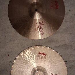 Dvě mosazné činely typu hi-hat o průměru 14". Horní činel nese červené nápisy „PAISTE 2002“ a „TOP SOUND EDGE HI-HAT 14"“. Spodní činel má v horní čá…