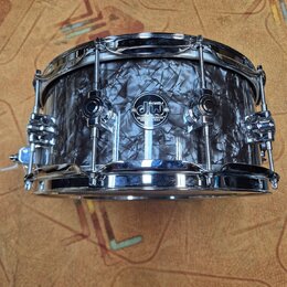 Fotografie znázorňuje malý buben s černobílým mramorovým povrchem a chromovaným kováním. Na korpusu je umístěno kulaté logo s nápisy drums DW, CUSTOM…