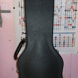 Černý tvrdý kufýr na kytaru s texturovaným povrchem. Ve spodní části je bílý nápis Gibson USA. Kufýr má připevněnou černou plastovou rukojeť a kovové…