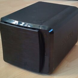 Černý, kompaktní reproduktor nebo subwoofer s hranatým tvarem a zaoblenými rohy. Na horní části je vyražený nápis "BASS" a na pravém boku je viditeln…