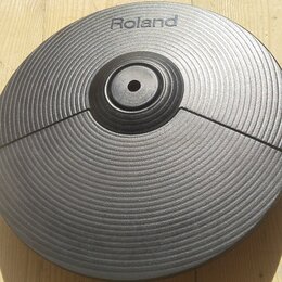 Černý gumový pad elektronického činelu s koncentrickým žebrováním. V horní části je bílý nápis Roland. Povrch vykazuje mírné známky opotřebení a v pr…