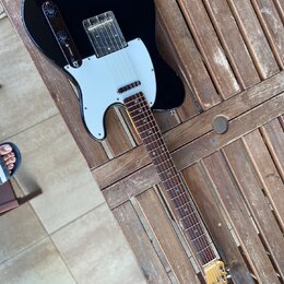 Černá elektrická kytara typu Telecaster s bílým pickguardem a hnědým hmatníkem. Na hlavě kytary je nápis "Spirit" a pod ním "TELECASTER". Povrch čern…
