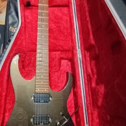 Elektrická kytara s tmavým, kovovým povrchem v červeně vystlaném tvrdém kufru. Na hlavě hmatníku je vidět nápis "ESP". Kytara má dva humbuckery, trem…