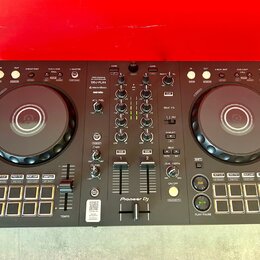 Černý DJ kontrolér s dvěma jog-koly a centrálním mixážním sekcí. Na přístroji jsou nápisy PERFORMANCE DJ CONTROLLER, DDJ-FLX4, rekordbox a serato, v…
