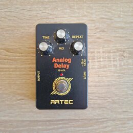 Černý efekt pedál s nápisy Analog Delay, SE-ADL a ARTEC. Obsahuje tři bílé ovládací knoflíky s popisky TIME, MIX a REPEAT. V dolní části je kruhové l…