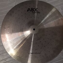 Kovový činel stříbrné barvy s viditelným rýhováním a jamkovaným povrchem. V horní části je černý nápis ABX Cymbals a v dolní části text 16" 46CM CRAS…