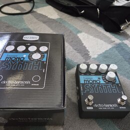Na fotografii je efekt pedál Bass Mono Synth značky electro-harmonix v černé barvě s bílými nápisy. Vedle pedálu je umístěna jeho originální krabice…