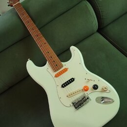 Bílá elektrická kytara s hnědým hmatníkem a bílým pickguardem. Na hlavě je viditelné logo "Squier". Nástroj má tři snímače, tři ovládací knoflíky a p…