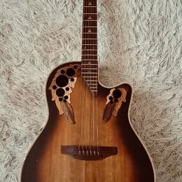 Akustická kytara s vyřezávanými otvory v horní desce místo klasického rozetového otvoru. Nástroj má tmavě hnědý přechodový povrch (sunburst) a hmatní…