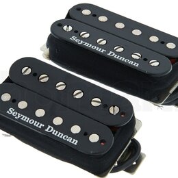 Dva elektrické kytarové snímače typu humbucker v černé barvě s černými plastovými kryty. Na spodní části obou snímačů je bílý nápis Seymour Duncan. S…