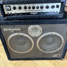 Černý basový kombozesilovač značky BEHRINGER, model ULTRABASS 3X4500H. Horní část tvoří zesilovač s ovládacími prvky a nápisem 450-WATT BASS AMPLIFIE…