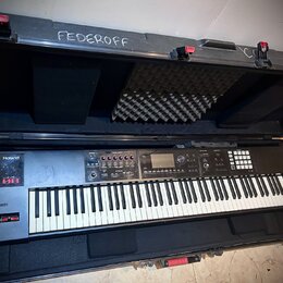 Černý digitální klavír značky Roland, model JD-800, umístěný v černé transportní bedně s polstrováním. Na levé straně je vidět logo Roland a červený…