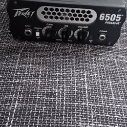 Černý kompaktní kytarový zesilovač s nápisy Peavey a 6505 PIRANHA™. Na předním panelu jsou tři ovládací knoflíky s popisky GAIN, EQ a VOLUME, přepína…