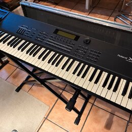 Černý digitální klavír Roland XP-80 Music Workstation na černém kovovém stojanu. Nástroj má standardní klávesnici a horní panel s displejem, tlačítky…
