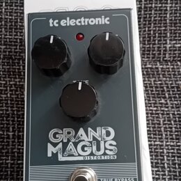 Kytarový efekt pedál v tmavě šedém provedení s bílými nápisy. Na horní hraně je logo tc electronic a uprostřed název modelu GRAND MAGUS DISTORTION. P…