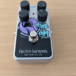 Stříbrný efekt pedál s černým předním panelem a čtyřmi černými ovládacími knoflíky. Na panelu je nápis Electro-Harmonix NEW YORK CITY, USA a grafický…