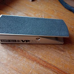 Stříbrný volume pedál s černým, hrubým povrchem šlapáku. Na boku je uveden nápis ERNIE BALL, logo v kruhu a označení VPJR CE. Zařízení vykazuje mírné…