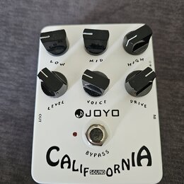 Bílý efekt pedál značky JOYO s nápisem CALIFORNIA SOUND a označením BYPASS. Pedál má šest černých otočných ovladačů s popisy LOW, MID, HIGH, LEVEL, V…