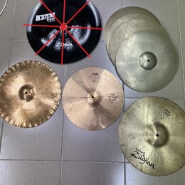 Sestet činelů v různých barvách a velikostech. Černý činel nese nápisy „Pitch Black“ a „Zildjian“. Jeden z mosazných činelů má nápisy „PAISTE“, „404“…