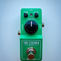 Zelený efekt pedál s nápisy TONE, LEVEL a OVERDRIVE u ovládacích knoflíků. Na spodní části je uveden název modelu TUBE SCREAMER MINI a logo Ibanez. N…