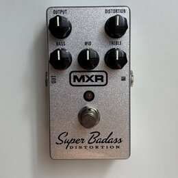 Stříbrný efekt pedál s kovovým, třpytivým povrchem. Na horní části jsou čtyři černé otočné ovladače s nápisy OUTPUT, DISTORTION, BASS, MID a TREBLE.…