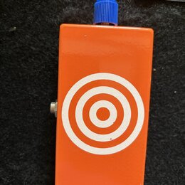Oranžový efekt pedál s modrým ovládacím knoflíkem. Na přední straně je bílý grafický symbol v podobě soustředných kruhů (terč). Povrch je hladký, bez…