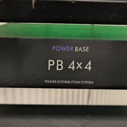 Černý rackový rozvodč rač s nápisy POWER BASE, PB 4x4 a POWER DISTRIBUTION SYSTEM. Zařízení je přišroubované do rackového stojanu pomocí čtyř šroubů.…