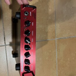 Červený basový zesilovač s nápisy THRUST a BQ500. Na předním panelu jsou ovládací knoflíky s popisky GAIN, THRUST, BASS, LO-MID, HI-MID, TREBLE a MAS…