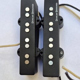 Dvě černé elektrické snímače typu rail s kovovými póly. Na obou je svisle napsán bílý text DUNCAN DESIGNED. Snímače mají připojené vodiče v černé a b…