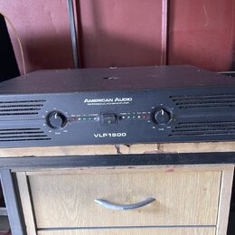 Černý výkonový zesilovač v kovovém šasi s nápisy AMERICAN AUDIO a PROFESSIONAL POWER AMPLIFIER. Na předním panelu je uprostřed označení modelu VLP150…