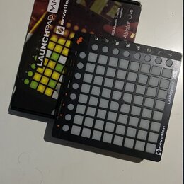 Černý MIDI kontrolér Novation Launchpad Mini s mřížkou bílých podsvícených políček. Na pravém okraji je svisle napsáno LAUNCHPAD MINI a v pravém doln…