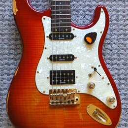Elektrická kytara s červeně-žlutým sunburst povrchem a bílým perleťovým pickguardem. Na tříech snímačích je uveden nápis LEVINSON. Kytara má zlatý ha…