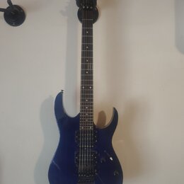 Modrá elektrická kytara s černým hmatníkem a černými hardwaremi. Na hlavě je nápis Ibanez. Kytara má dva humbuckery, jeden ovladač hlasitosti a jeden…