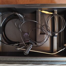 Černý plastový kufřík s vnitřními přihrádkami, ve kterém se nachází headset s mikrofonem. Sestava obsahuje tenký černý kabel, mikrofonní rameno s čer…