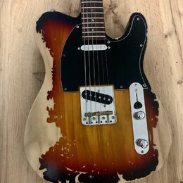 Elektrická kytara typu Telecaster s dřevem v přirozené barvě a tmavě hnědým, nepravidelným „spáleným“ vzorem. Má černý pickguard a jeden snímač u mos…