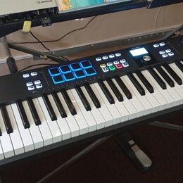 Černý MIDI kontrolér s klávesnicí, umístěný na stojanu. Na levé straně je nápis KEYLAB ESSENTIAL 61 a v horní části značka ARTURIA. Přístroj obsahuje…