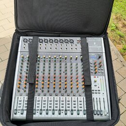 Stříbrný mixážní pult umístěný v černém polstrovaném přenosném pouzdře. Na zařízení jsou viditelné nápisy "MAIN MIX", "SUBGROUP" a řada číselných ozn…