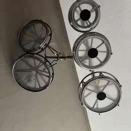 Sada pěti malých kovových bubnů v chromovaném provedení, které jsou upevněny na společném kovovém držáku. Bubny mají průhledné membrány a černé střed…