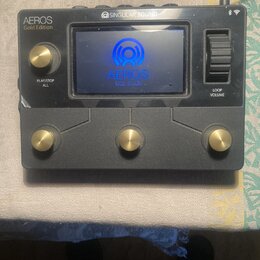 Černý loop pedal s kovovým povrchem a zlatými ovládacími prvky. Na zařízení jsou nápisy „AEROS Gold Edition“, „SINGULAR SOUND“ a na displeji text „AE…