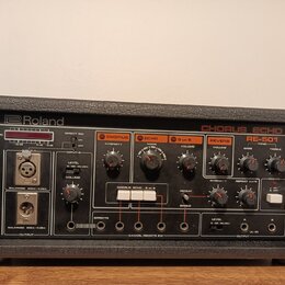 Černý efektový procesor Roland CHORUS ECHO RE-501 v robustním pouzdře. Přední panel obsahuje různé ovládací knofíky, přepínače a vstupní/výstupní kon…