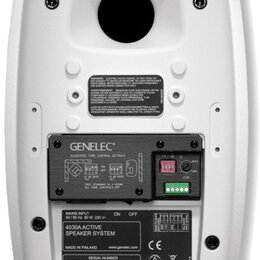 Zadní strana bílého studiového monitoru. Na černém panelu je nápis GENELEC a tabulka SUGGESTED TONE CONTROL SETTINGS s popisem FREE STANDING IN A ROO…