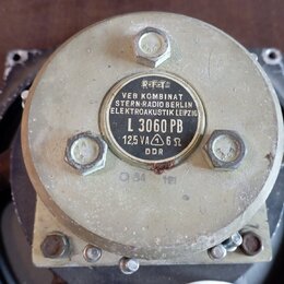 Detailní pohled na zadní část reproduktoru s kovovým krytem v béžové barvě. Uprostřed je černý štít s bílým nápisem VEB KOMBINAT STERN-RADIO BERLIN E…