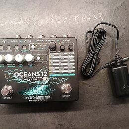 Stříbrný efekt pedál s nápisy OCEANS 12, DUAL STEREO REVERB a značkou electro-harmonix NEW YORK CITY, USA. Horní panel obsahuje pět bílých otočných o…