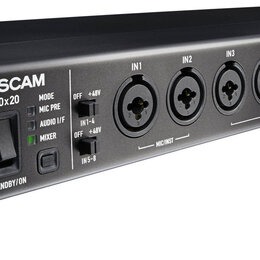 Černý rackový audio rozhraní s kovovým šasi a stříbrnými bočními konzolami. Na předním panelu je nápis TASCAM US-20x20, přepínač STANDBY/ON a osm kom…