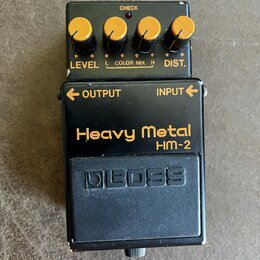Černý efekt pedál s nápisy Heavy Metal a HM-2. Horní část obsahuje čtyři žluté ovládací knoflíky s popisky LEVEL, COLOR MIX (označený L a H) a DIST.…