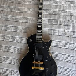 Černá elektrická kytara s gold hardwarem a bílými blokovými vložkami na hmatníku. Na hlavě je nápis Epiphone a logo, na snímači je vidět nápis Epipho…