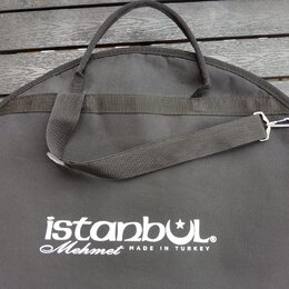 Černý textilní obal na cimbál s rukojetí a ramenním popruhem s kovovým háčkem. Na povrchu je bílý nápis istanbul Mehmet MADE IN TURKEY. Povrch textil…