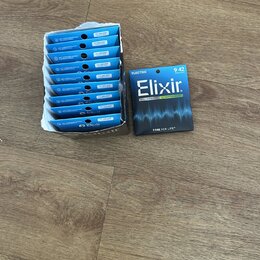 Fotografie zobrazuje sadu kytarových strun v modrých obalech. Na jednom z obalů je čitelně napsáno ELECTRIC, Elixir., 9-42 SUPERLIGHT, NICKEL PLATED…